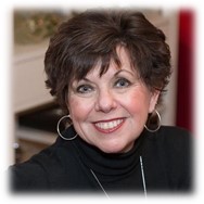 A woman with short hair wearing black is smiling.