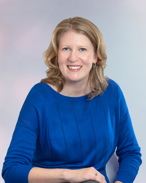 A woman in blue sweater smiling for the camera.