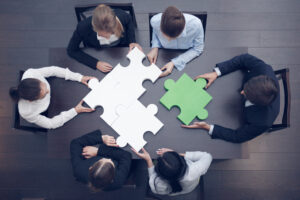 A group of people sitting around a table with puzzle pieces.