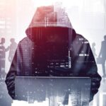 A person in a hooded jacket holding a laptop.
