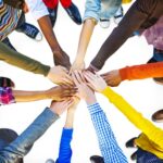 A group of people holding hands in the middle of a circle.