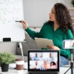 A woman is holding a pen and writing on a whiteboard