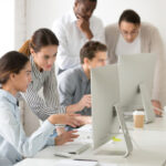 A group of people sitting at a table with computers.