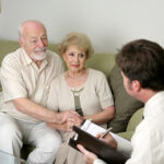 A man and woman sitting on the couch with an older couple.