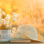 A hat and flowers on the table in front of some grass