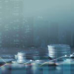 A blurry image of stacks of coins in front of the city skyline.