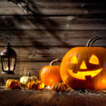 A wooden table with pumpkins and lanterns on it.
