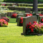 A cemetery with many headstones and flowers growing.